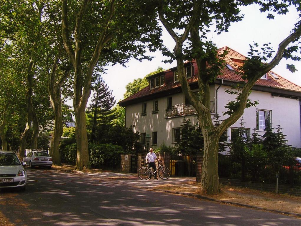 a person riding a bike in front of a house at Apart Pension Babelsberg in Potsdam