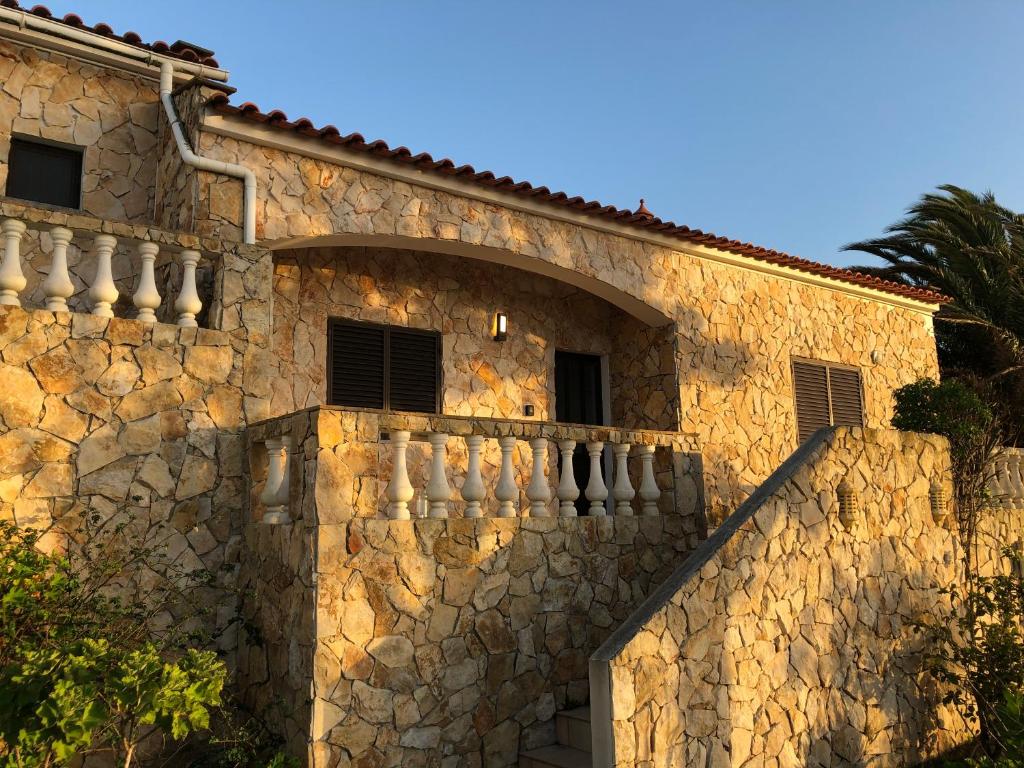 un edificio de piedra con una pared de piedra y un balcón en Terra da Eira - Villa mit Pool Western Algarve, en Vila do Bispo