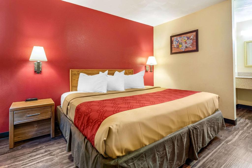 uma cama grande num quarto com uma parede vermelha em Rodeway Inn em Jeffersonville