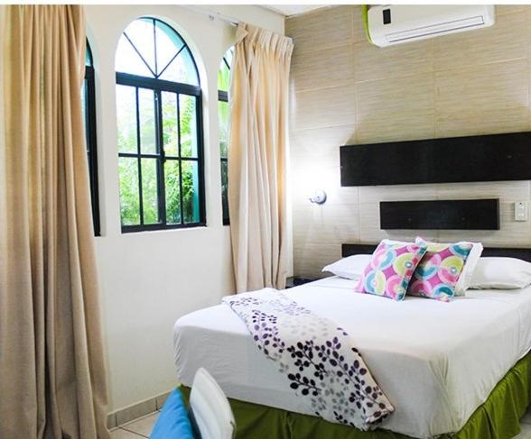 1 dormitorio con cama con almohadas y ventana en Villa del Angel Hotel en San Salvador