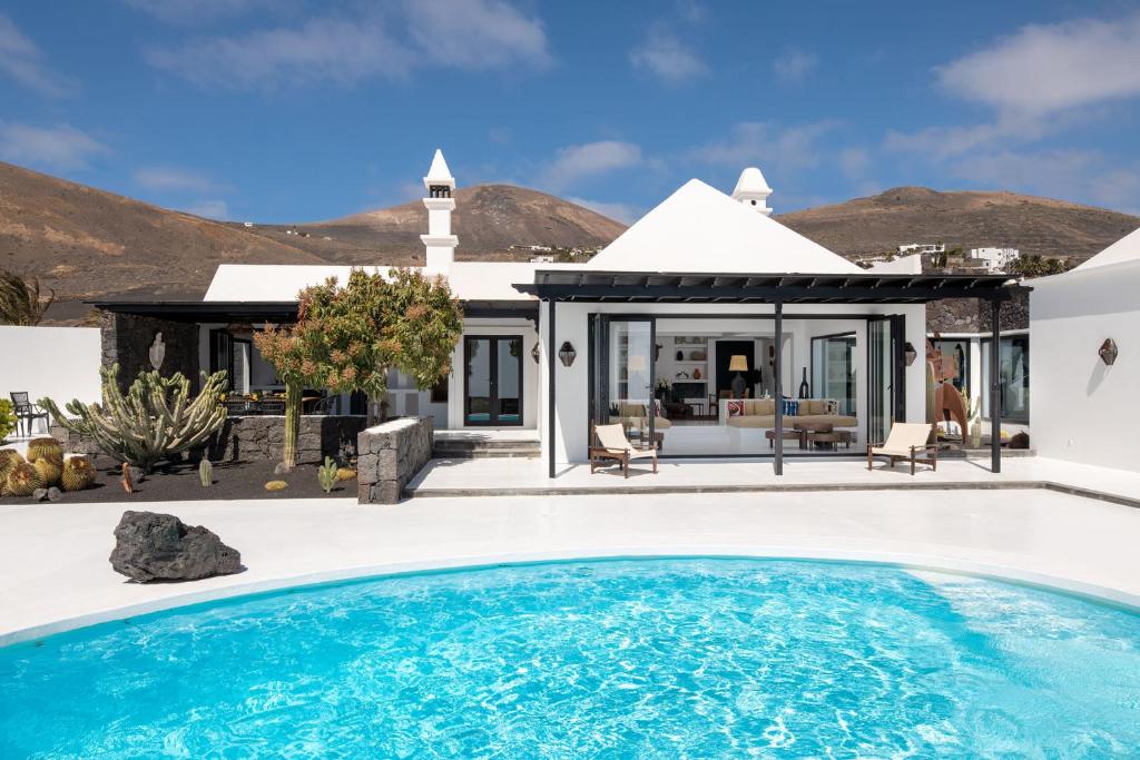 a villa with a swimming pool in front of a house at La Cabaña in La Asomada