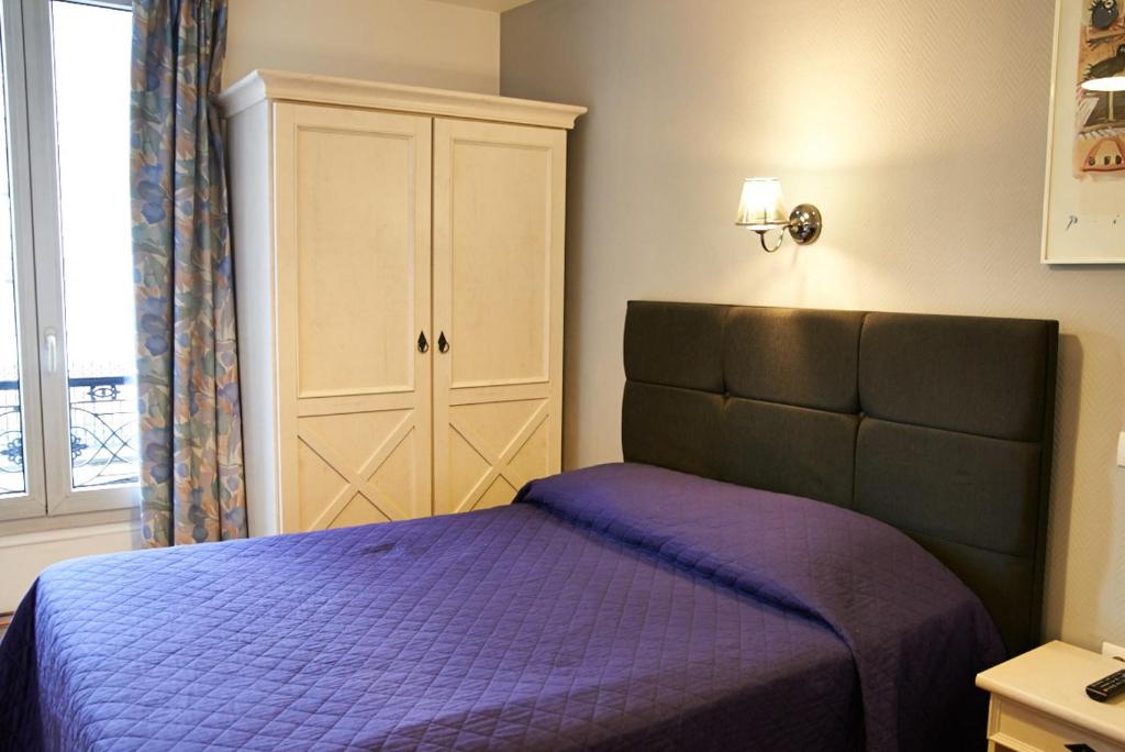 a bedroom with a purple bed and a cabinet at Hotel Luxor in Issy-les-Moulineaux