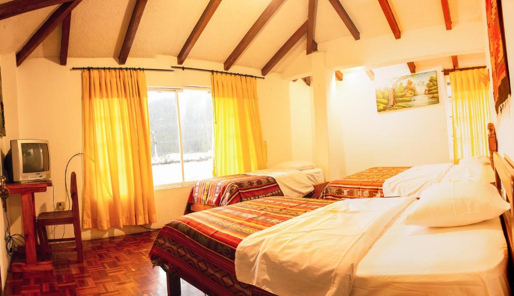 Cette chambre comprend 2 lits et une télévision. dans l'établissement Casa del Huesped, à Otavalo