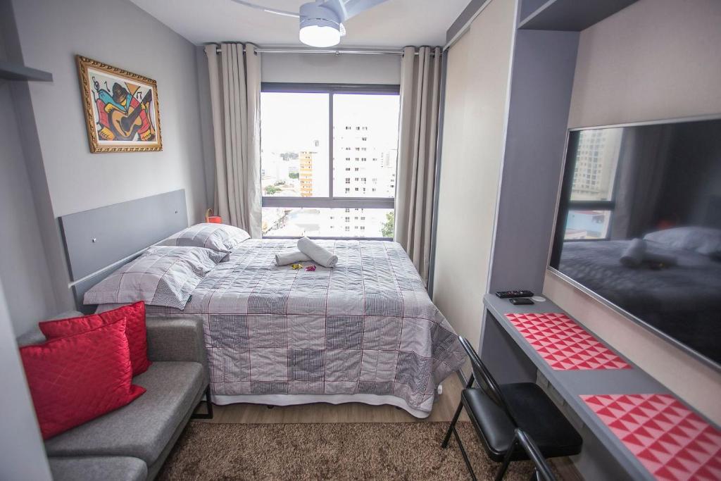 ein Schlafzimmer mit einem Bett, einem Sofa und einem Fenster in der Unterkunft Studio Central - ALL1403 in Curitiba
