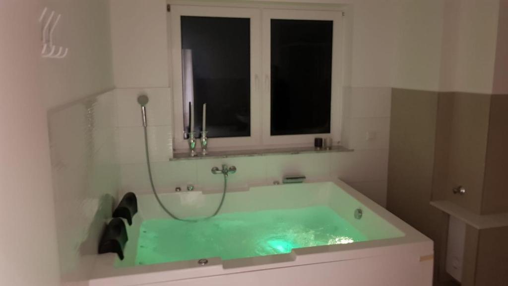 uma banheira verde numa casa de banho com uma janela em Luxuswohnung mit Jacuzzi Nähe Flughafen Köln/Bonn em Troisdorf