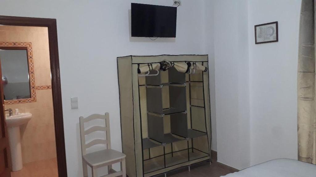 sypialnia ze szklaną szafką i krzesłem w obiekcie Hostal VILLA CARBULA w mieście Almodóvar del Río