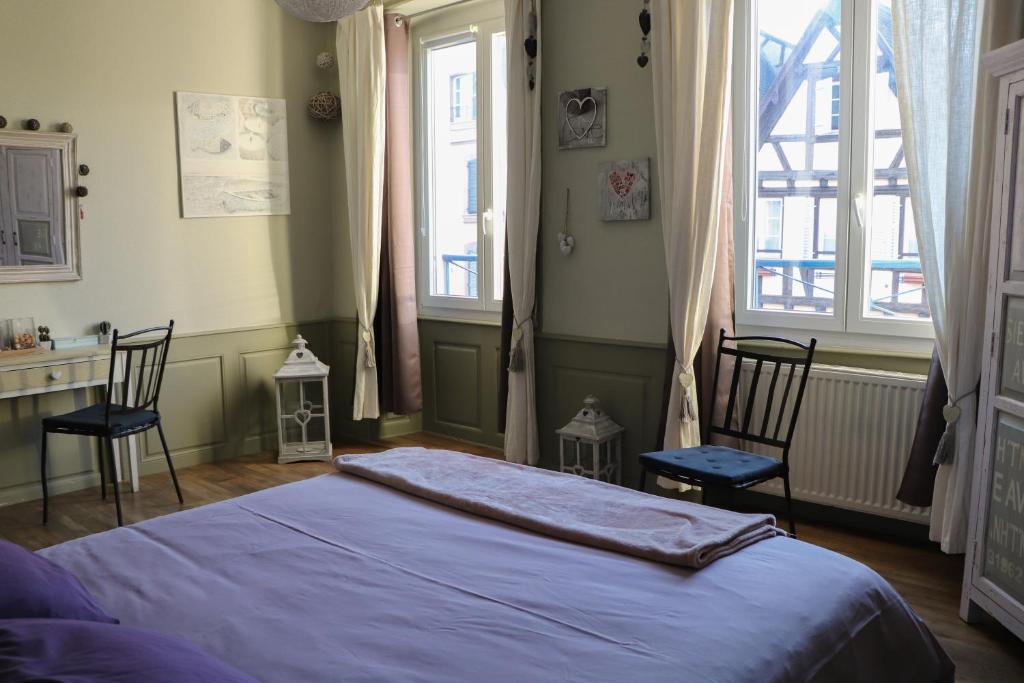 a bedroom with a bed and two chairs and windows at Gite Moka45 Centre historique "Climatisé" in Colmar