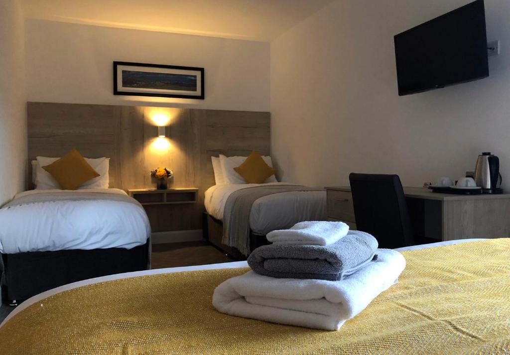 um quarto de hotel com duas camas e toalhas numa mesa em McNaughton Guestrooms em Ballymena