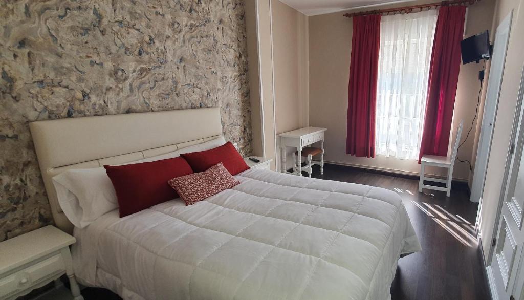 a bedroom with a large white bed with red pillows at Hotel Prados in Lugo