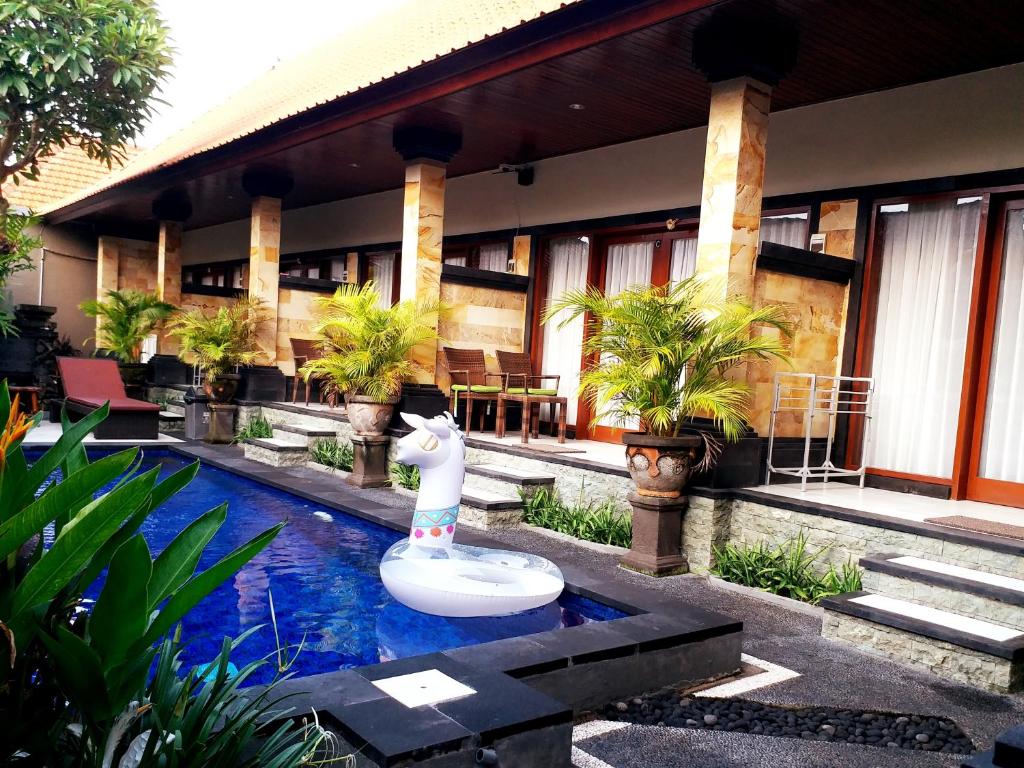 a pool in front of a house with a fountain at Kamboja Homestay in Sanur