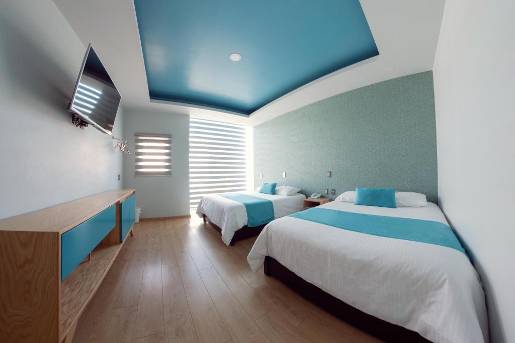 una camera con due letti e un soffitto blu di HOTEL AZUL AGAVE ad Arandas