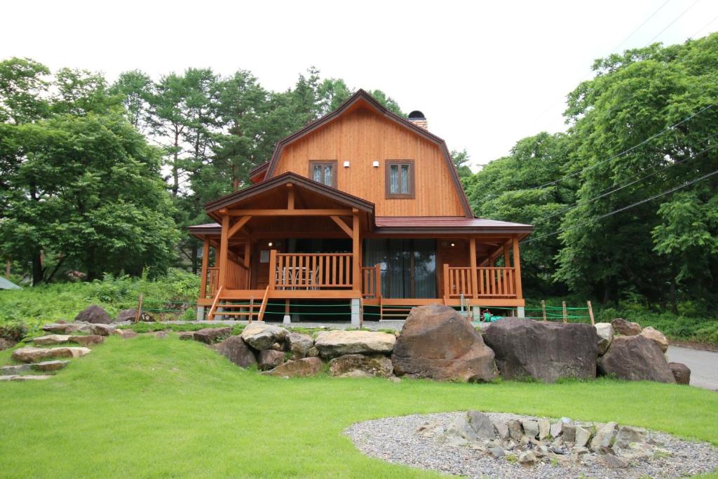 una gran casa de madera con un patio con rocas en Cottage All Resort Service / Vacation STAY 8450 en Inawashiro