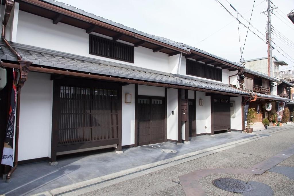 un edificio blanco con puertas marrones en una calle en Machiya no Yado Iroha, en Nagahama