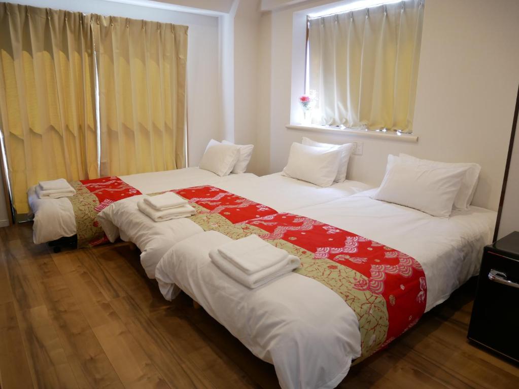 two beds in a hotel room with white and red sheets at Tokyo shinjukutei Hotel Asahi gruop 東京新宿亭ホテル in Tokyo