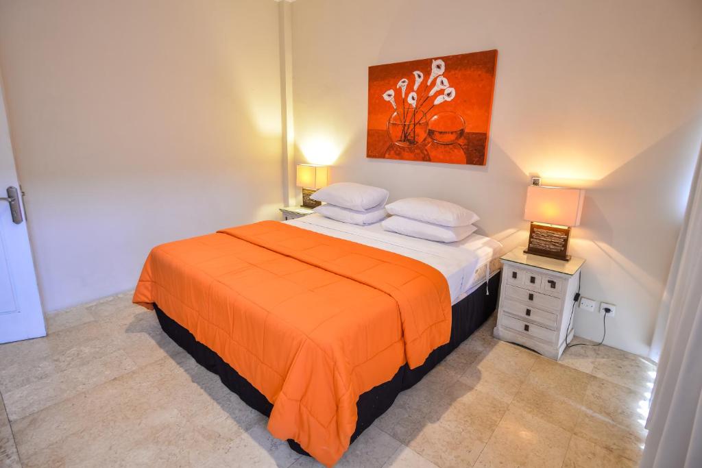 a bedroom with a bed with an orange blanket at Bali Mystique Hotel & Apartment in Seminyak