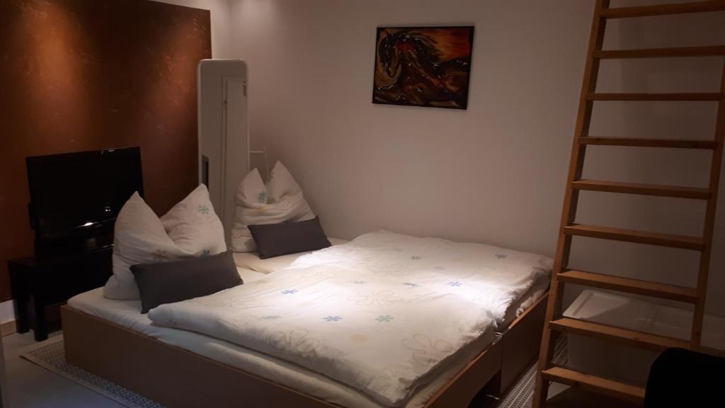 1 cama con sábanas blancas y almohadas en una habitación en Fewo Be Happy! Kleiner Bungalow mit eigener Terrasse im Grünen! en Stockhausen-Illfurth