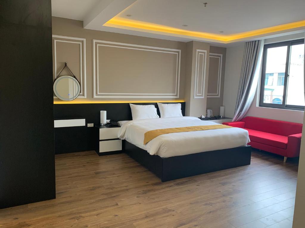 a bedroom with a large bed and a red couch at Hotel Villa Ju in Hanoi