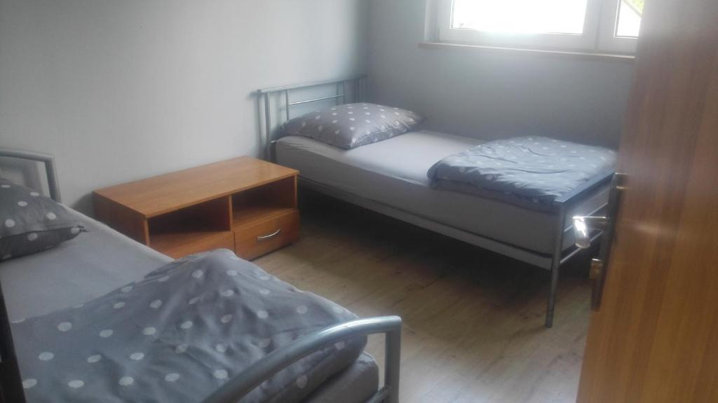 Cette petite chambre comprend deux lits et une table. dans l'établissement Hostel Lisięcice, à Lisiecice