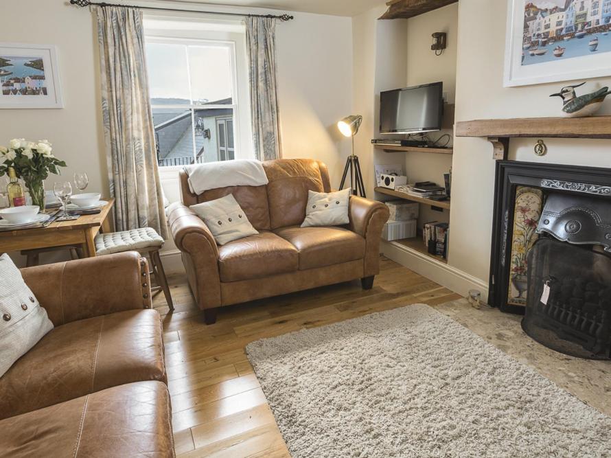 ein Wohnzimmer mit Sofa und Kamin in der Unterkunft Pixie Cottage in Dartmouth