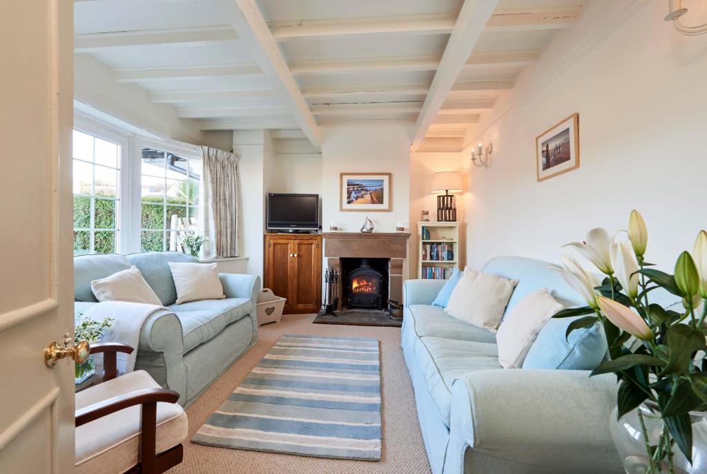a living room with two blue couches and a fireplace at Rigg Cottage in Whitby