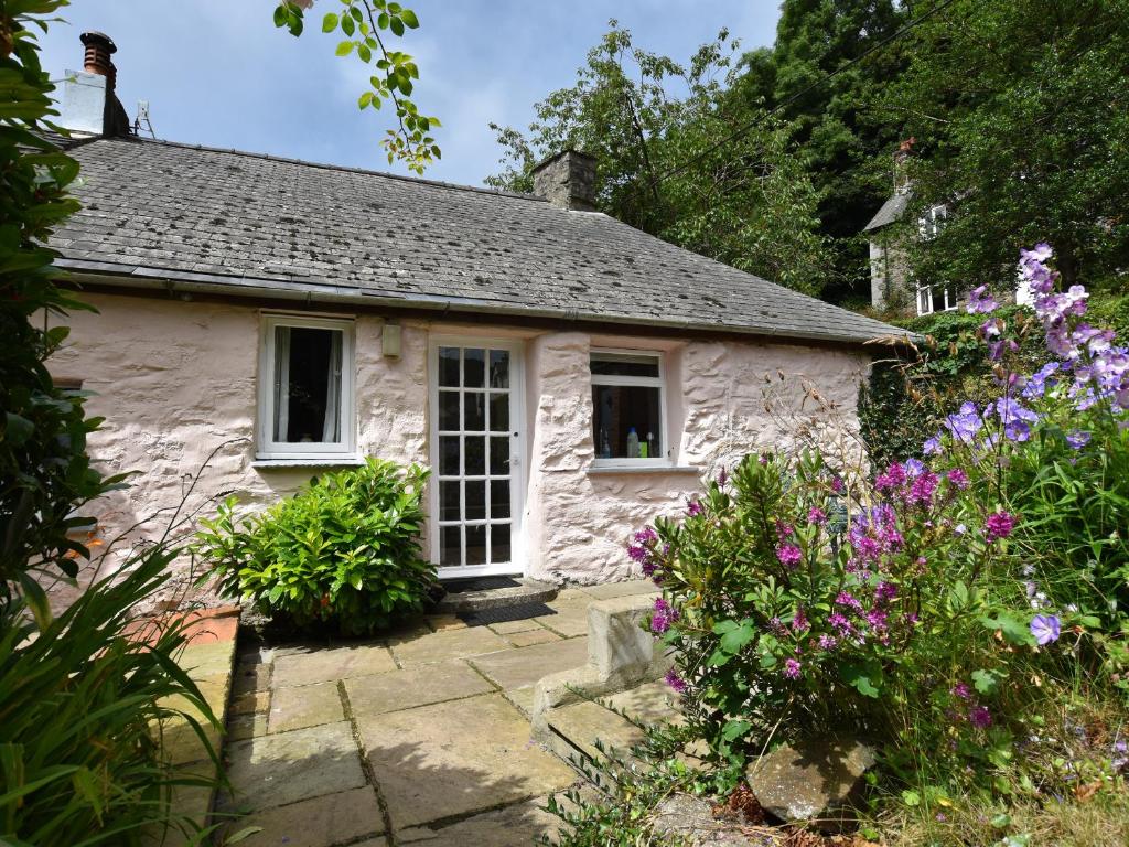 a stone cottage with flowers in front of it at Milkwood Cottage in Fishguard