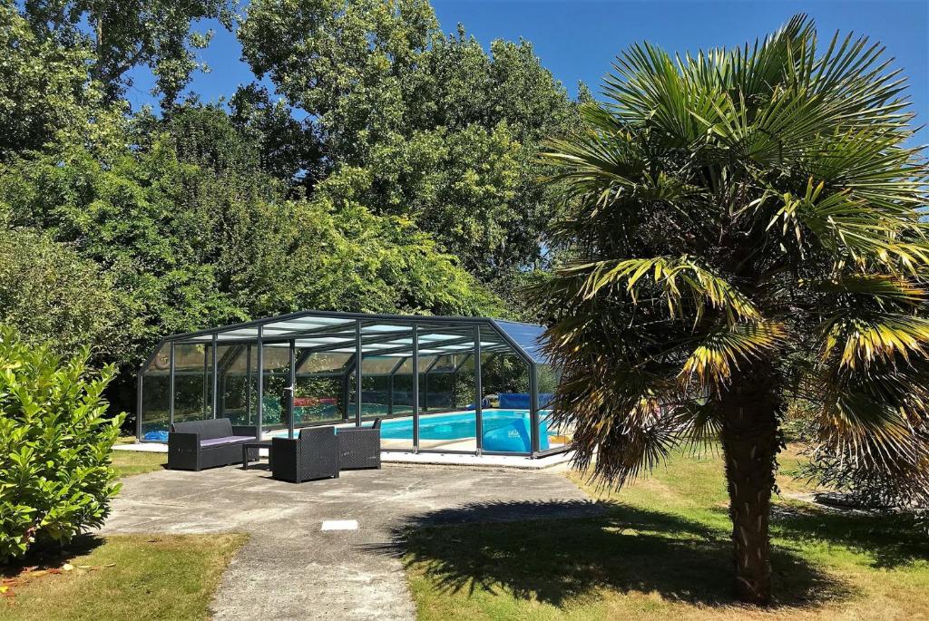 una palmera y una piscina en un pabellón en Villa de plain-pied avec WIFI, piscine privée sous abris haut à PLEUMEUR-BODOU - Ref 461 en Pleumeur-Bodou