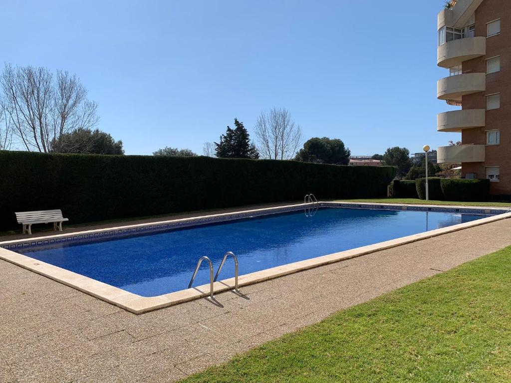 uma piscina com um banco ao lado de um edifício em BOOK FORUM I SALOU em Salou