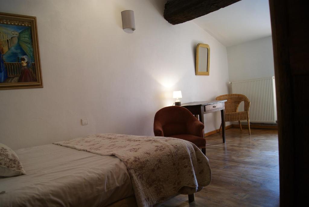 Un dormitorio con una cama, un escritorio y una silla. en La piscine de tonton Jean, en Caunes-Minervois