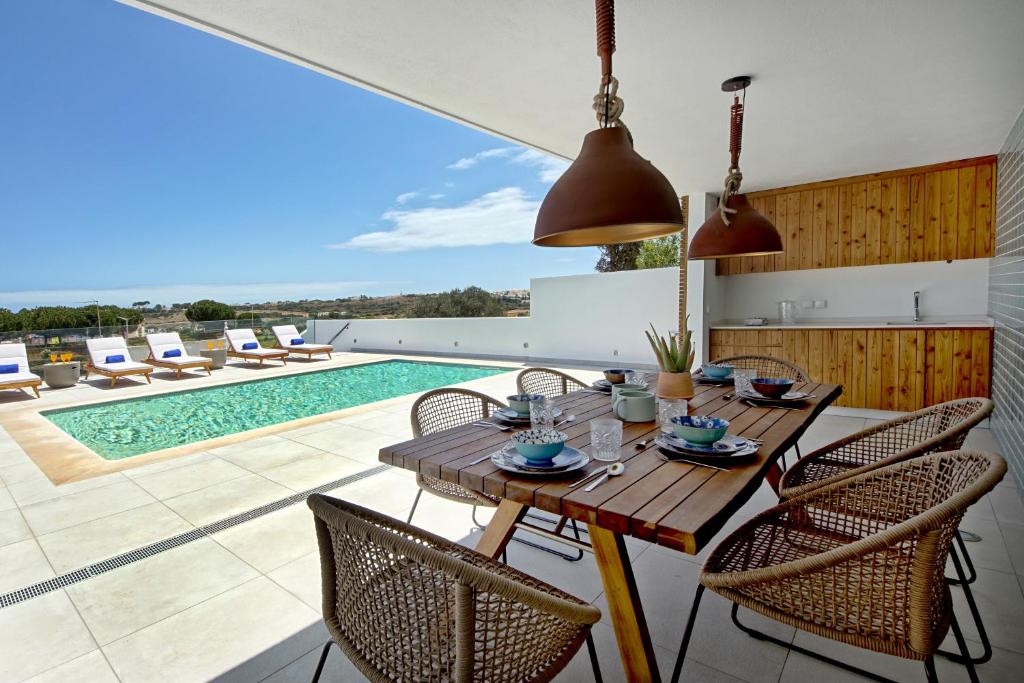 uma sala de jantar com mesa e cadeiras e uma piscina em Villa Ocean Marina, Panoramic and heatable Pool em Albufeira