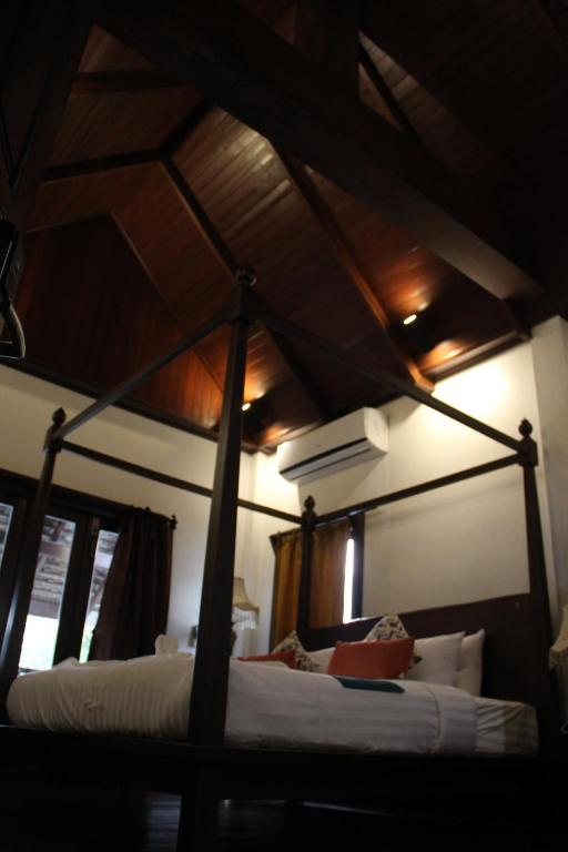 1 dormitorio con cama con dosel y sábanas blancas en Alana Luang Prabang en Luang Prabang
