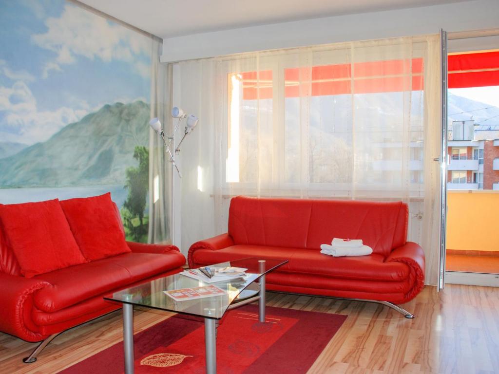 ein Wohnzimmer mit 2 roten Stühlen und einem Tisch in der Unterkunft Apartment Residenza Lido-24 by Interhome in Locarno