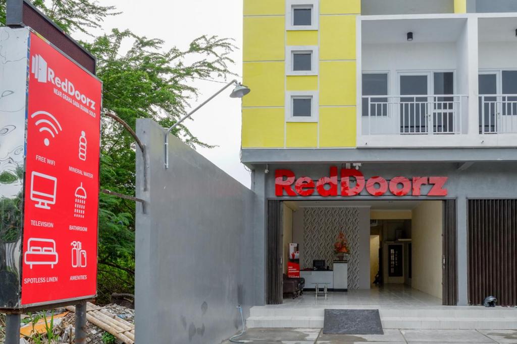 um edifício vermelho e amarelo com um sinal em frente em RedDoorz near Graha Saba Buana Solo em Kadipiro