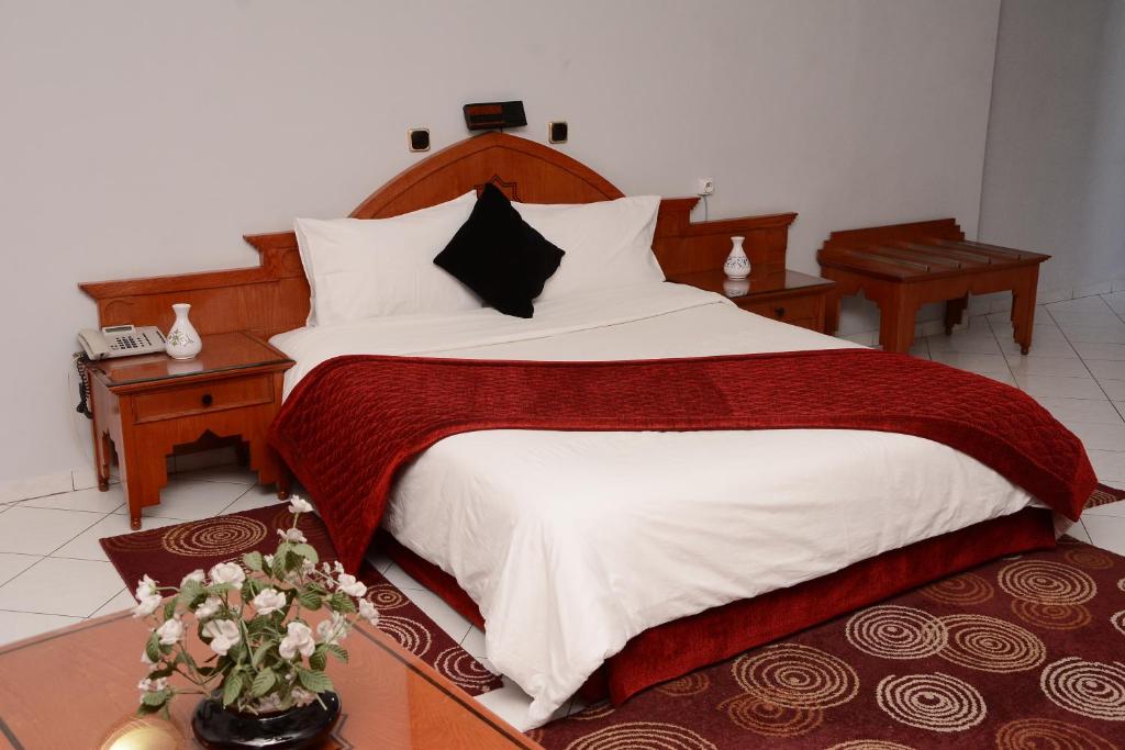 um quarto com uma cama grande com lençóis brancos e vermelhos em Hotel Bouregreg em Rabat