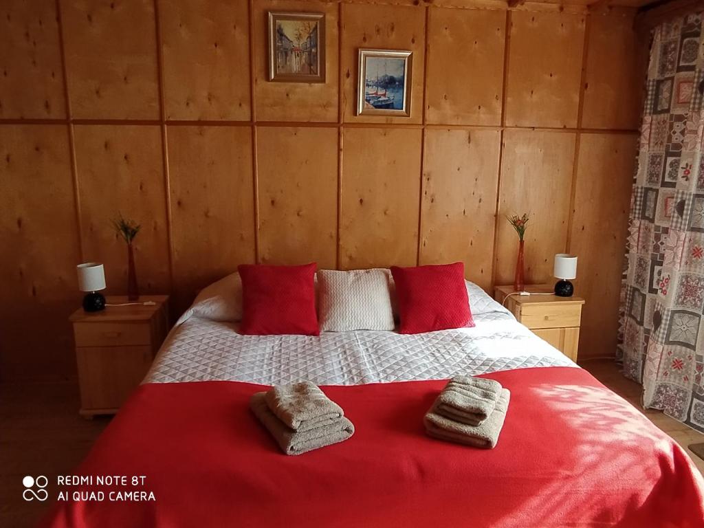 a bedroom with a red bed with towels on it at Apartament Widok in Czarna Góra