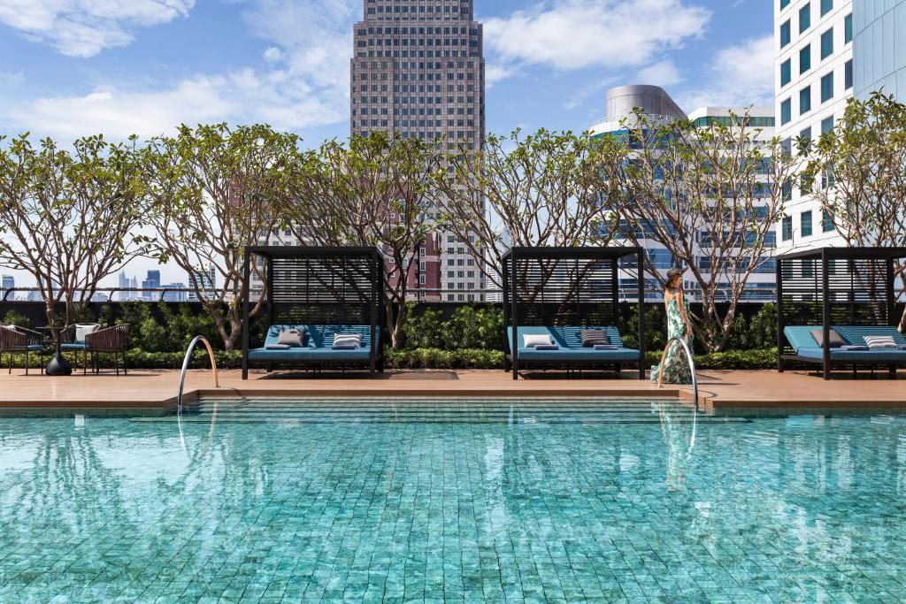 A rooftop-style outdoor pool with cabana loungers and a dense city skyline beyond.