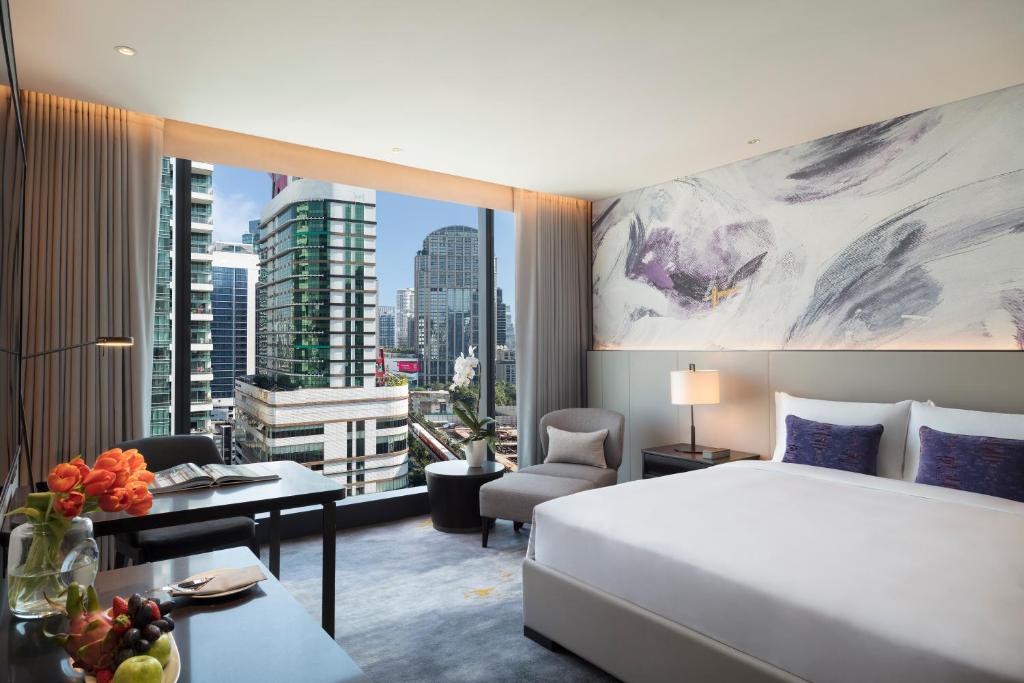 Corner-view king room with a wide urban outlook, dining-style desk and lounge chair.