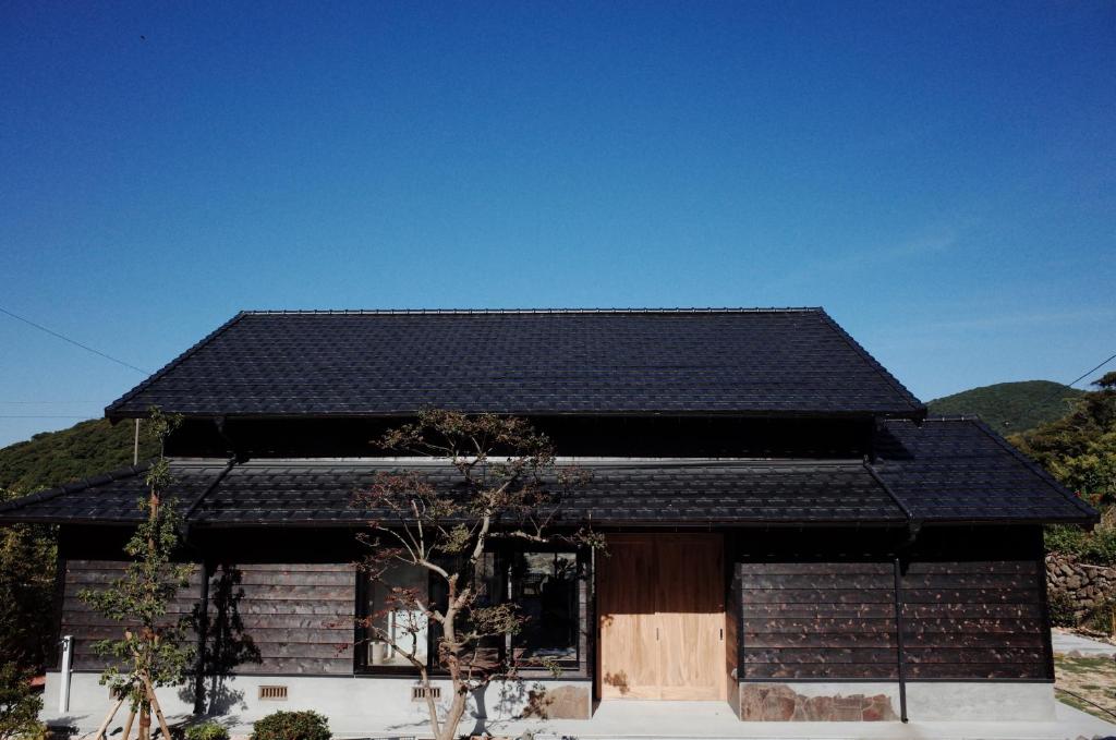 una casa con un techo negro encima en Okune, en Goto