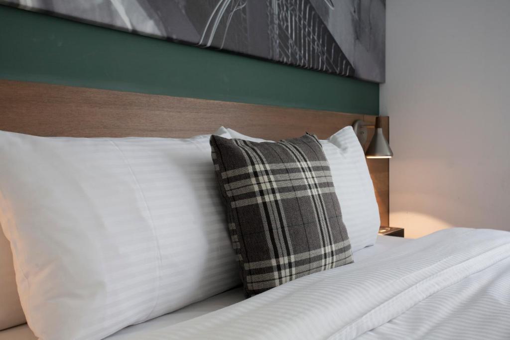 a bed with white pillows and a plaid pillow at P&amp;F Hotel in Taichung