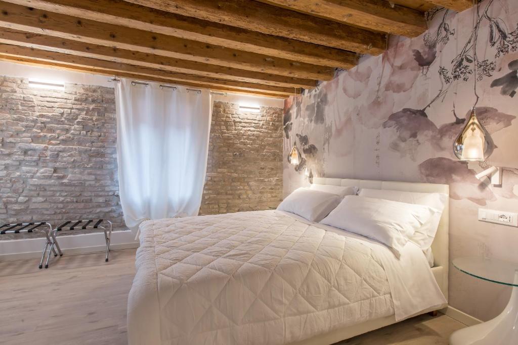 een slaapkamer met een wit bed en een bakstenen muur bij Hermes San Marco in Venetië