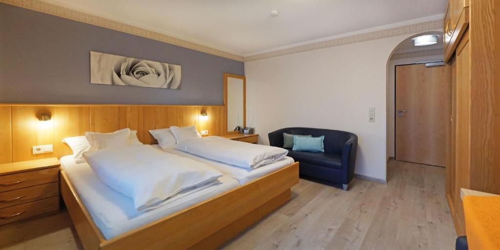 a bedroom with a large bed and a chair at Haus Carola in Bad Füssing