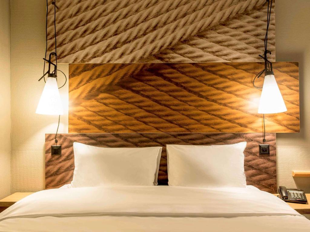 ein Schlafzimmer mit einem großen Bett mit zwei Leuchten darüber in der Unterkunft ibis Zurich Adliswil in Zürich