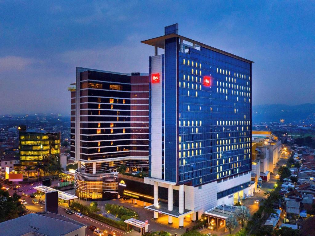 a tall blue building in a city at night at Ibis Bandung Trans Studio in Bandung