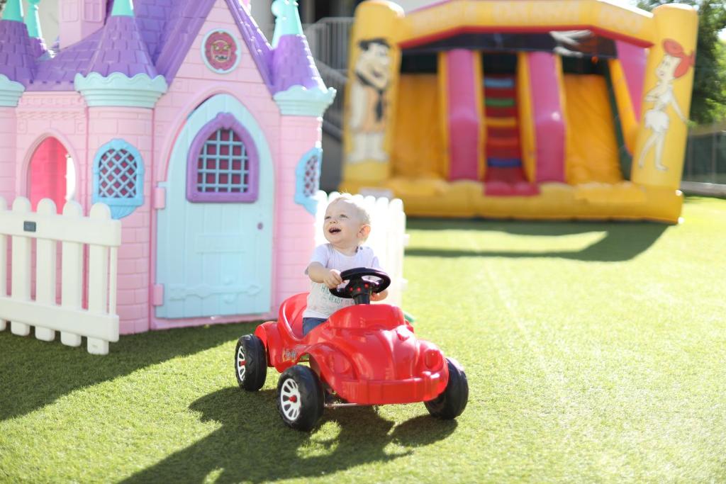 a baby riding a toy car in front of a toy house at Hotel Internazionale in Bellaria-Igea Marina