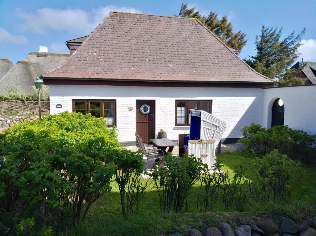 a white house with a table and chairs in the yard at Ferienwohnung Kiekin in Wenningstedt