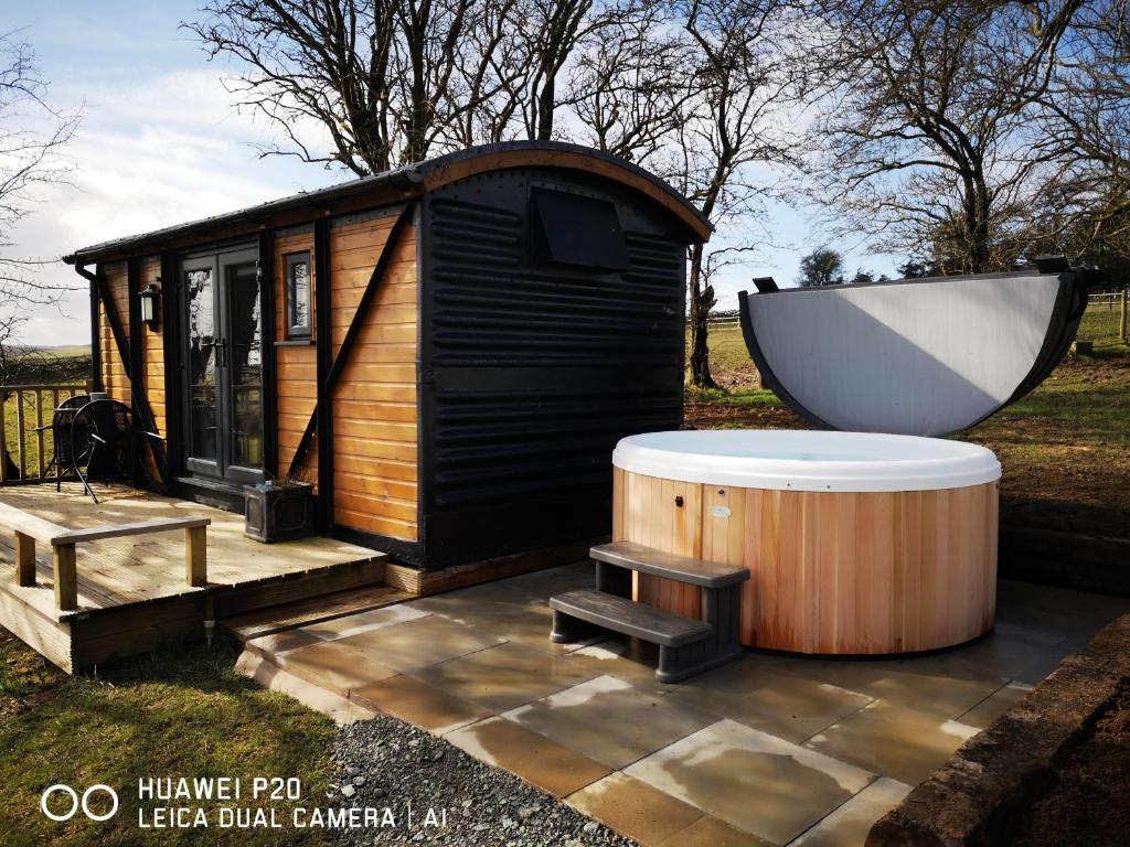 uma banheira ao lado de uma pequena cabina com uma banheira em pen-rhos luxury glamping "The Hare Hut" em Llandrindod Wells