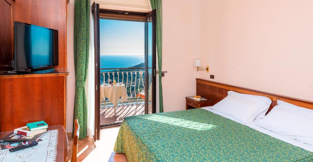 a bedroom with a bed and a television and a balcony at Hotel Montana in SantʼAgata sui Due Golfi