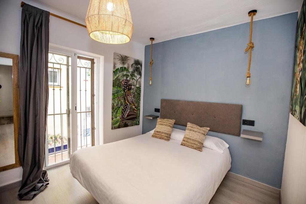 1 dormitorio con 1 cama grande y pared azul en Hostal The Monkey Room, en Marbella