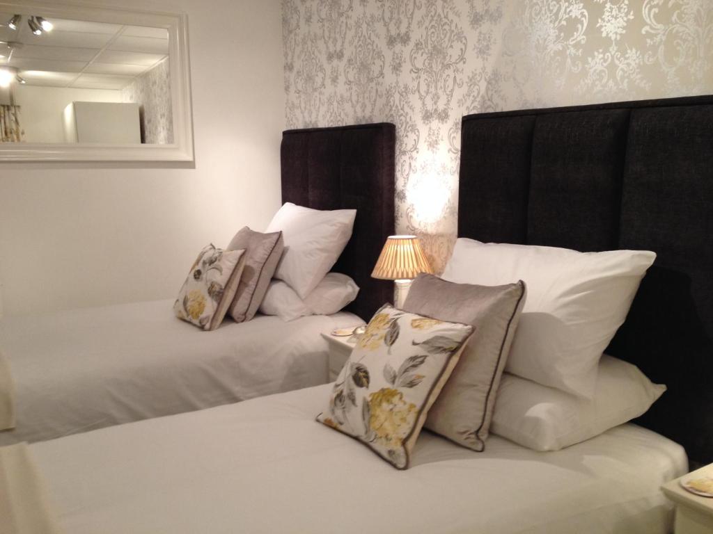1 dormitorio con 2 camas con almohadas y lámpara en New Masons Arms en Leeds