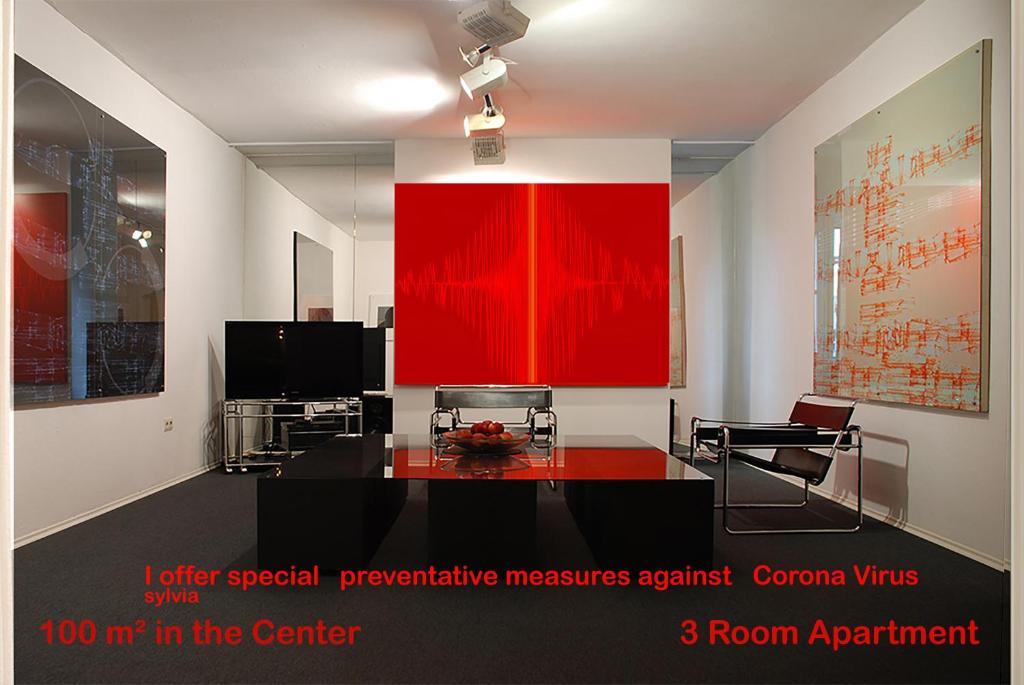 una sala de estar con una pared roja y una mesa. en Artist Residence Schwabing en Múnich