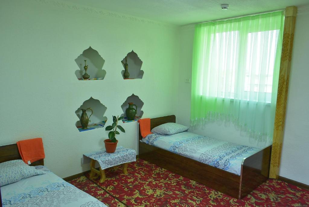 una camera con 2 letti singoli e una finestra di Masturabonu Ravshan a Bukhara